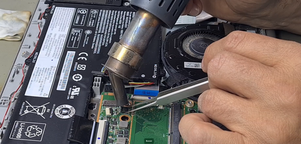 técnico desoldando chip BIOS de placa base de portátil Lenovo con soldador de aire caliente para reprogramación externa